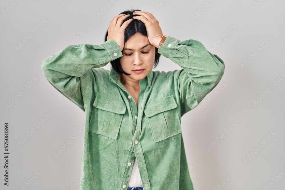 Poster young asian woman standing over white background suffering from headache desperate and stressed beca