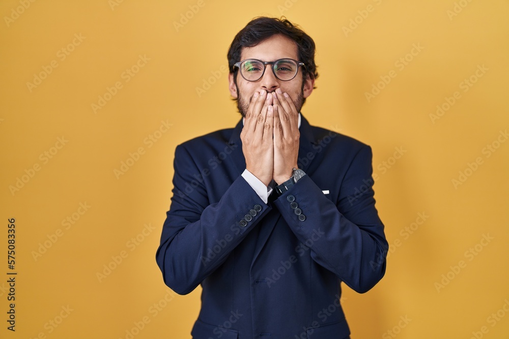 Sticker Handsome latin man standing over yellow background laughing and embarrassed giggle covering mouth with hands, gossip and scandal concept