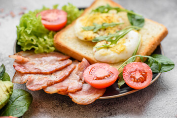 Delicious healthy lunch consisting of bacon, toast, eggs and tomatoes