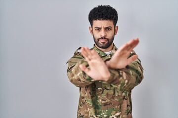 Arab man wearing camouflage army uniform rejection expression crossing arms and palms doing negative sign, angry face