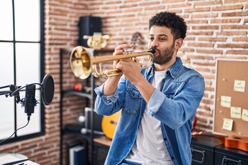 Young arab man musician playing trumpet at music studio - obrazy, fototapety, plakaty