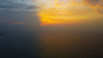 Aerial view of the sunset in an orange sky with clouds. Beautiful background for tourism and advertising. Tropical coast