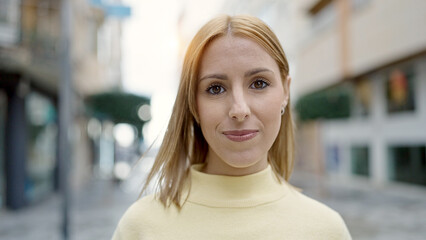 Fototapeta premium Young blonde woman standing with serious expression at street