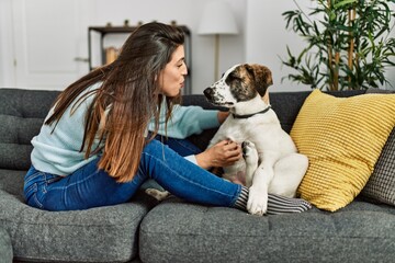 Young woman hugging dog sitting on sofa at home