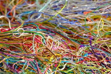 Multi-colored tangled threads background. Macro or close up of colorful tangled threads. Needlecraft silk thread ropes. Colored natural thread pile for sewing cloth scattered randomly like spaghetti.