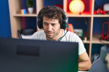 Young hispanic man streamer playing video game using computer at music studio