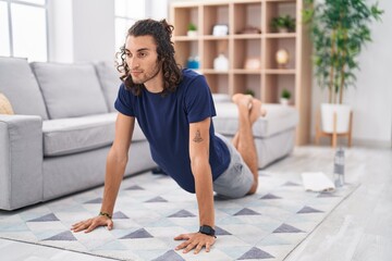 Young hispanic man training yoga at home