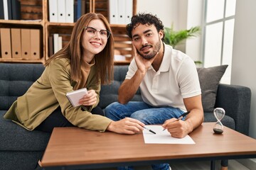 Man and woman having psychology session writing on paperwork at psychology center