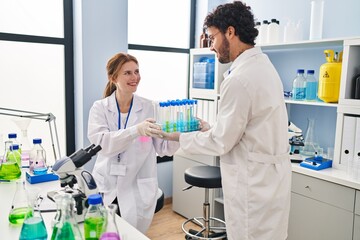 Man and woman scientist partners holding test tubes at laboratory