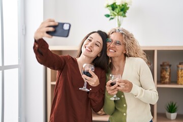 Two women mother and daughter drinking wine make selfie by smartphone at home