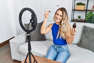 Young woman recording skin care tutorial by smartphone at home