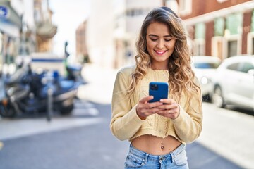 Young woman smiling confident using smartphone at street