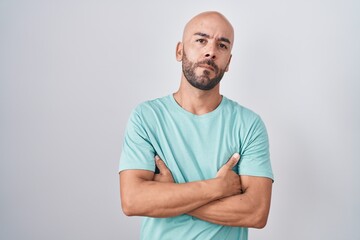 Middle age bald man standing over white background skeptic and nervous, disapproving expression on face with crossed arms. negative person.