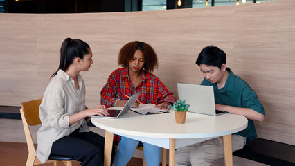Three students sitting doing exam exercises in laptop computer jot down explanation exam in notebook, woman turned man's sheath man turned look at woman woman dodged both them laughing.
