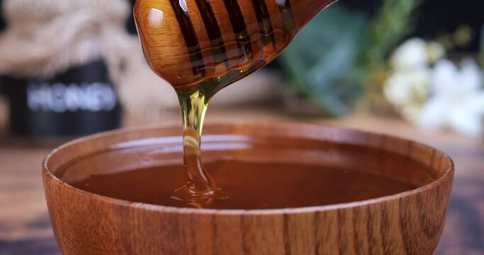 Honey spoon coming out of the bowl full of honey. Honey contains many nutrients, antioxidants, improves heart health, wound care, offers antidepressant and anti-anxiety benefits. 4k