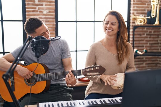 Man and woman musicians playing classical guitar and tambourine at music studio