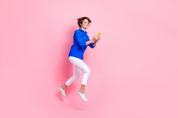 Full body size photo of young funny entrepreneur woman jumping run with her new impact resistant smartphone isolated on pink color background