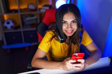 Young beautiful arab woman streamer using computer and smartphone at gaming room