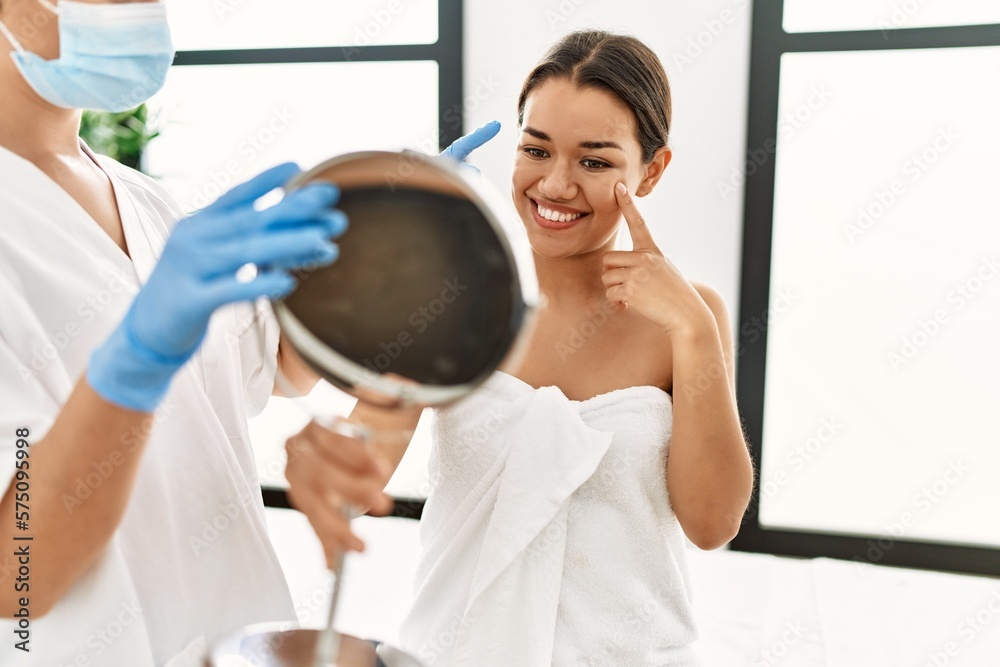 Sticker young latin woman wearing towel looking face on mirror at beauty center