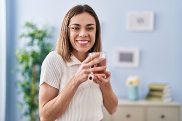 Young beautiful hispanic woman smiling confident drinking tea at home