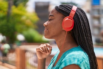 Fototapeta premium African american woman smiling confident listening to music at park