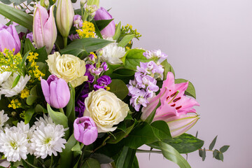 Closeup flowers background - blank greeting card or invitation with rose flowers, tulips and lily in pink and purple colors, copy space.