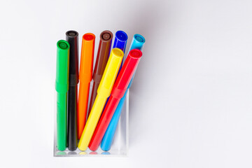 Felt pens of different colors are in a glass. On a white background.