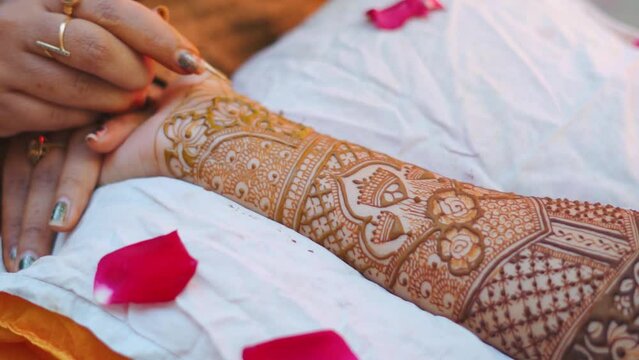 Close up shot of Mehndi artist drawing beautiful mehndi in Indian bride's hand on occasion of wedding in India. Indian bride hand with mehndi design. Heena tattoo in bride hand