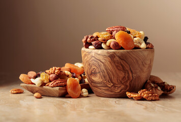 Fototapeta na wymiar Dried fruits and nuts on a beige ceramic table.
