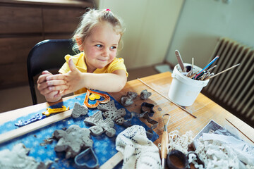 Little girl is creating products from ceramics clay. Making ceramics heart. Support creative work