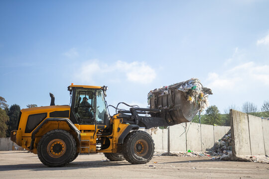Heavy construction machine, front end loader moving along recycling center area, close up view. Waste management industry concept.