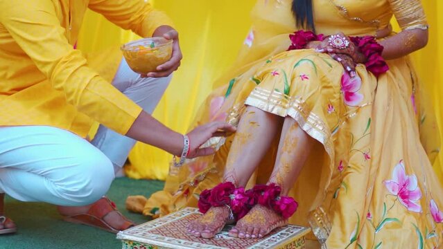 Turmeric is being applied to the bride's legs in India called as Haldi Ceremony. An Indian wedding tradition. Indian Hindu wedding. Family And Friends Applying Turmeric To Bride. 