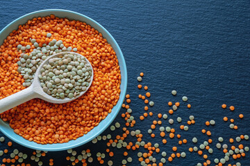 Red and green lentils in plate on dark table.  Flat lay, copy space