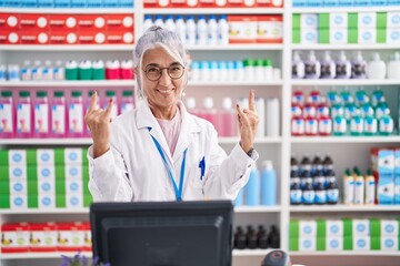 Middle age woman with tattoos working at pharmacy drugstore shouting with crazy expression doing...
