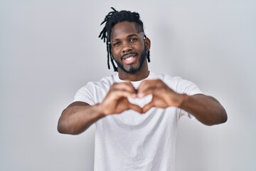 African man with dreadlocks wearing casual t shirt over white background smiling in love doing...