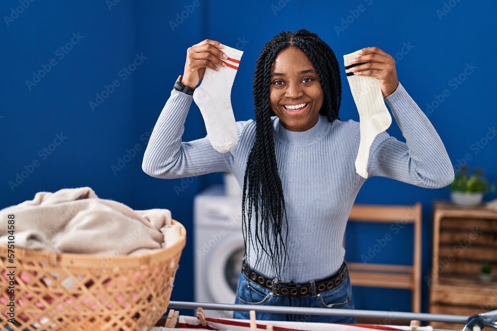 Sticker african american woman holding socks smiling and laughing hard out loud because funny crazy joke.