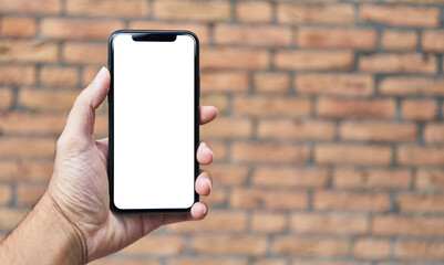 Man holding smartphone showing white blank screen over isolated brick background