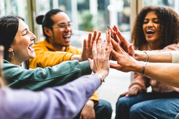 Multiracial happy young people stacking hands-Group of diverse friends  having fun unity together indoors at table of community-Human resources Concept Creative and Relationship Youth Culture 