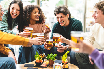 Multiracial friends drinking and toasting beer at brewery bar pub-Happy diverse people cheering glasses and having fun enjoying happy hour celebrating party-Beverage life style concept with guys 