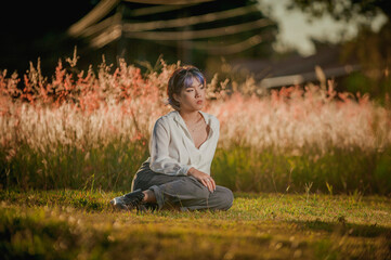 Asian young lady sitting at the outdoors flowered field.