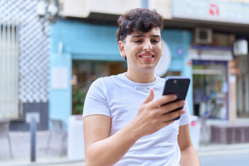 Non binary man smiling confident using smartphone at street