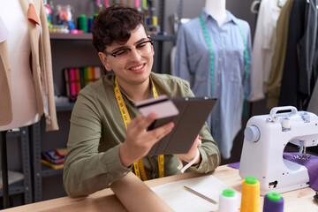 Non binary man tailor using touchpad and credit card at atelier