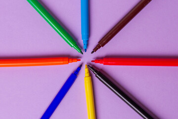 Fototapeta premium Felt-tip pens without caps of different colors on a purple background. Arranged in a circle.