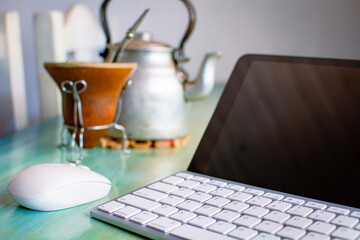 Estudiando en casa, laptop mouse y equipo de mate sobre la mesa, pava y mate tradicional de porongo, trabajando en la mañana. © Daniel