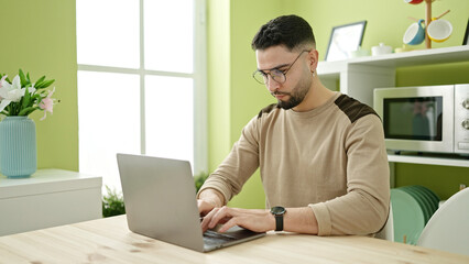 Young arab man using laptop sitting on table at home