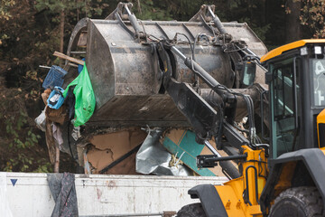 Skid steer loader moving garbage at the landfill site, before processing waste material, sorting, treatment, or recycling
