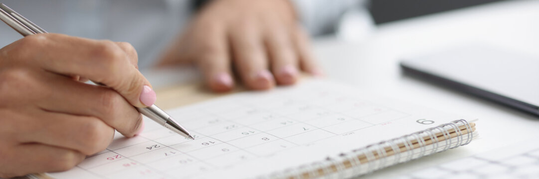 Closeup of person marking with pen and looking at date on calendar