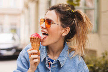 Close up portrait woman with high ponytail hold delicious pink ice cream in waffle cone outdoors....