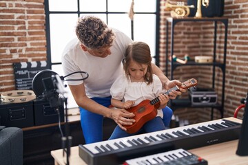 Fototapeta na wymiar Father and daughter playing ukulele at music studio
