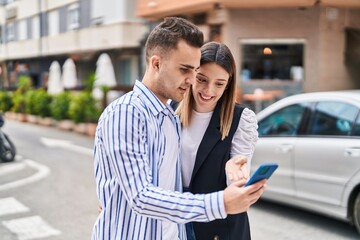 Man and woman couple using smartphone standing together at street